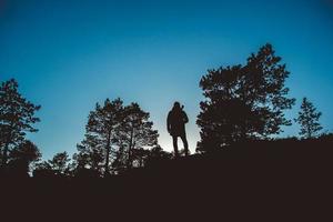 sagoma di un uomo nella foresta su uno sfondo di cielo blu foto