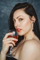 bella donna con un bicchiere di vino su sfondo grigio foto