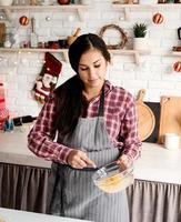 giovane donna latina che sbatte le uova cucinando in cucina