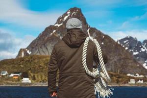 uomo con una corda sulla spalla su uno sfondo di montagne foto