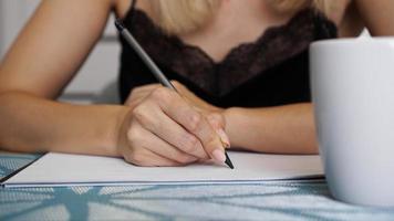la mano della donna usa la scrittura a matita su un foglio trasparente foto