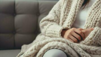 accogliente lana coperta su divano mano Tenere cuscino per rilassamento foto