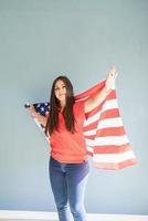 felice giovane donna con bandiera americana su sfondo blu foto