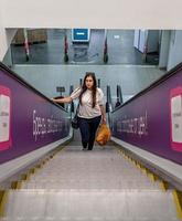 giovane donna in piedi sulla scala mobile nel centro commerciale shopping foto
