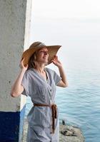 donna felice in abiti estivi in piedi in riva al mare che guarda lontano foto