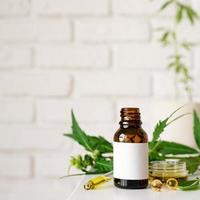 olio di CBD e foglie di cannabis cosmetici vista frontale su sfondo arancione foto