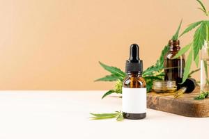 olio di CBD e foglie di cannabis cosmetici vista frontale su sfondo arancione foto