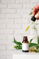 olio di CBD e foglie di cannabis cosmetici vista frontale su sfondo arancione foto