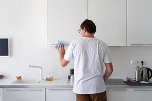 uomo che pulisce le superfici della cucina foto