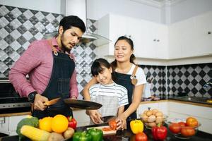 la famiglia felice aiuta a cucinare il pasto insieme nella cucina di casa. foto