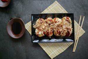 takoyaki è un' giapponese cibo, fatto a partire dal Grano Farina Impasto, polpo carne, o altro ripieni, servito con salsa, Maionese e guarnizione nel il modulo di katsuobushi o legna pesce trucioli. foto