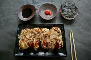 takoyaki è un' giapponese cibo, fatto a partire dal Grano Farina Impasto, polpo carne, o altro ripieni, servito con salsa, Maionese e guarnizione nel il modulo di katsuobushi o legna pesce trucioli. foto