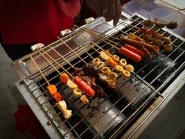 vario tipi di satay, spiedo, salsiccia, pelle, yakitori, pollo su caldo carboni. bakaran foto