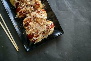 takoyaki è un' giapponese cibo, fatto a partire dal Grano Farina Impasto, polpo carne, o altro ripieni, servito con salsa, Maionese e guarnizione nel il modulo di katsuobushi o legna pesce trucioli. foto