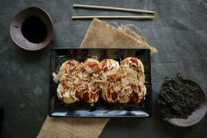 takoyaki è un' giapponese cibo, fatto a partire dal Grano Farina Impasto, polpo carne, o altro ripieni, servito con salsa, Maionese e guarnizione nel il modulo di katsuobushi o legna pesce trucioli. foto