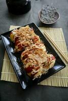 takoyaki è un' giapponese cibo, fatto a partire dal Grano Farina Impasto, polpo carne, o altro ripieni, servito con salsa, Maionese e guarnizione nel il modulo di katsuobushi o legna pesce trucioli. foto