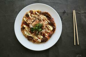 okonomyaki, tradizionale giapponese Pizza, giapponese caldo piatto Pizza a partire dal okonomiyaki. fatto di Farina quale è diluito con acqua o dashi, più cavolo, pollo uova, frutti di mare e fritte nel un' teppan foto