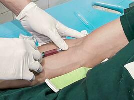 un' maschio infermiera è iniettare un' dolore mitigatore anestetico in un' del paziente mano foto