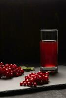 rosso succo a partire dal Viburnum nel un' bicchiere su un' nero sfondo. vicino Viburnum bacche.sane cibo foto