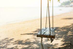 di legno swing su il spiaggia su un' tropicale spiaggia contro il sole luce, rilassante di il mare tropicale clima nel Tailandia estate foto