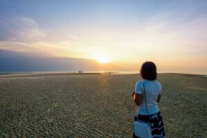 donna Guardando tramonto a il spiaggia foto