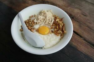 pollo porridge con fresco uovo come guarnizione con di legno sfondo foto