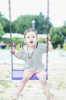 bambini giocare su all'aperto terreno di gioco nel scuola o asilo, attivo bambini nel colorato oscillazione, salutare estate attività per bambini nel soleggiato sera volta. foto