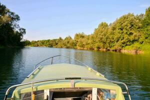 un' barca su il fiume con alberi e cespugli nel il sfondo foto