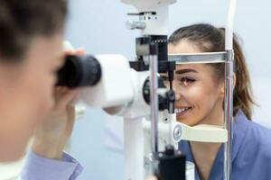 femmina medico oculista è controllo il occhio visione di attraente giovane donna nel moderno clinica. medico e paziente nel oftalmologia clinica. foto