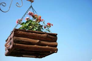 fioritura bianca e viola fiori nel di legno pentola sospeso con ferro polo nel naturale leggero giardino e blu cielo foto