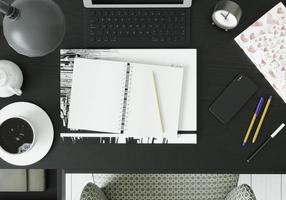 una stanza di lavoro con tablet, libri, penne e smartphone sul tavolo.