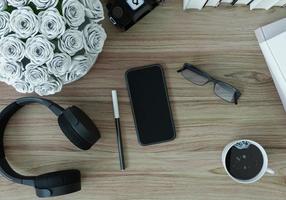 smartphone, cuffie, tazza di caffè, occhiali e penne posizionati foto