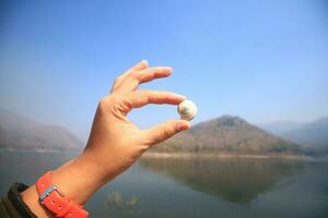 asiatico donna mano Tenere un' lumaca o nautilo e mollusco vicino il fiume e montagna nel nazionale parco a Tailandia foto