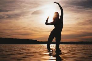 donna spensierata felice che gode del bel tramonto sulla spiaggia foto