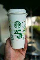 bangkok, Tailandia - ottobre 16, 2023 uomo Tenere riutilizzabile tazza, 25 anniversario, Starbucks Tailandia, ottenere 1 gratuito foto