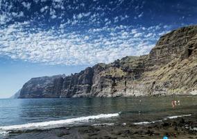 I turisti la balneazione a los gigantes vulcanica spiaggia di sabbia nera dalle famose scogliere naturali punto di riferimento nel sud dell'isola di tenerife spagna