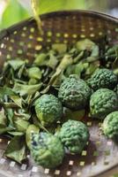 frutta fresca di lime kaffir tailandese e foglie secche in cesto di ingredienti rustici