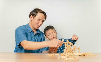 un ragazzo gioca con suo padre a casa con un puzzle di legno. foto
