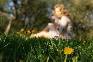donna carina riposa nel parco con i denti di leone - concentrati sul fiore nell'erba foto