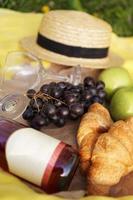 picnic sull'erba con croissant, vino rosato, cappello di paglia, uva
