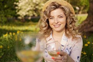 donne che tintinnano bicchieri con vino gustoso su sfondo chiaro foto
