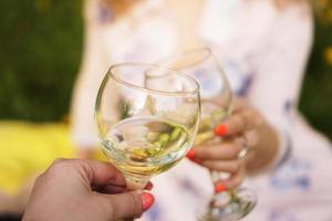 donne che tintinnano bicchieri con vino gustoso su sfondo chiaro foto