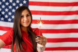 bella donna che tiene una stella filante sullo sfondo della bandiera degli Stati Uniti foto
