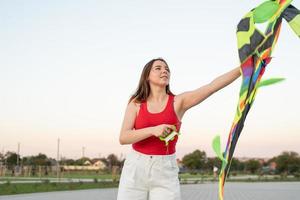 giovane donna che fa volare un aquilone in un parco pubblico al tramonto foto