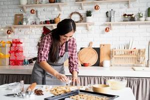 giovane donna bruna che cuoce i biscotti in cucina foto