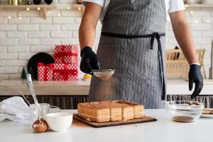 chef che cucina dessert in cucina versandoci sopra il cacao in polvere foto