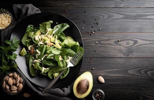 vista dall'alto di avocado fresco estivo e insalata di spinaci su legno nero foto