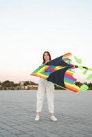 giovane donna che fa volare un aquilone in un parco pubblico al tramonto foto