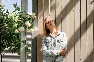 giovane donna in piedi in rose bianche in un giardino o in un parco foto