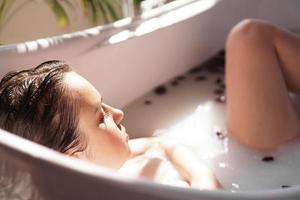 una ragazza attraente che si rilassa nella vasca da bagno su sfondo chiaro